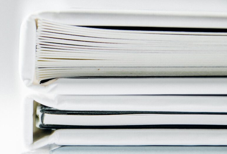 A stack of thick folders on a white surface